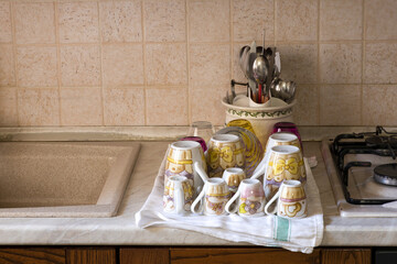 Tazze, tazzine e posate ad asciugare su uno straccio in cucina.