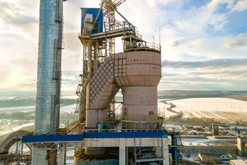 Aerial view of cement plant with high factory structure and tower crane at industrial production area.