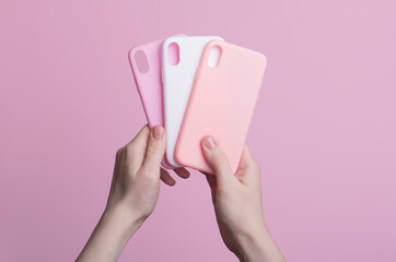 hands holding three colorful smartphone iPhone X cases isolated on pink background