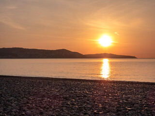 Lever de soleil et ciel de feu au-dessus du Cap Ferrat depuis une plage de la baie des anges à Nice sur la Côte d'Azur