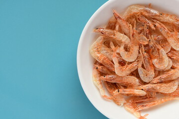 Dried sakura shrimp on light blue background.