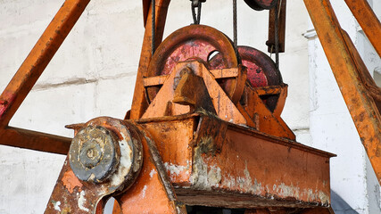 Details of lifting mechanism of rusty bucket grab in industrial plant. Steel wire rope and wheels closeup