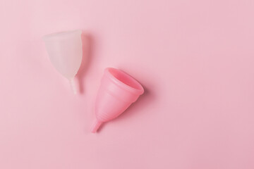 Two menstrual cups on the pink background. Decorated with a flower. Zero waste period concept.