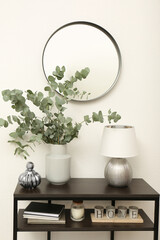 Modern console table with stylish decor and mirror on white wall in room. Interior design