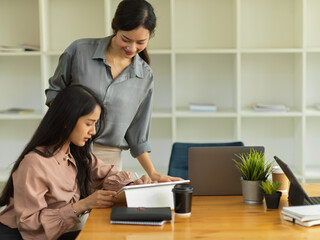 Two businesswoman discussing their work while origin together in meeting room
