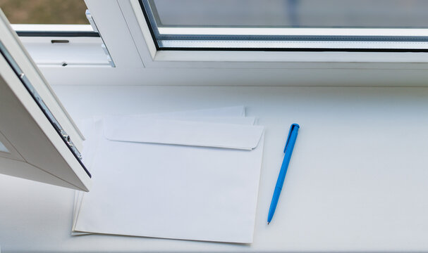 A letter envelope and a pen on the windowsill