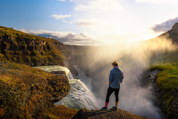 Young hiker standing at the edge of the Gullfoss waterfall in Iceland