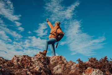 a hiking girl with a backpack on her back watches the morning from the top of the mountain