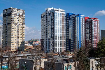 Fototapeta na wymiar Residential complexes with high-rise buildings against blue sky. In foreground is territory of preschool institution. Skyscrapers and ready-made infrastructure. Krasnodar, Russia - March 13, 2021
