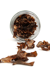Dried tamarind slices in a glass jar and scattered on ground isolated on white background