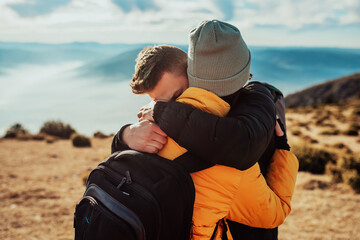 a young couple embracing standing on top of a mountain