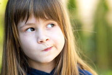 Close up portrait of pensive cute brunette child girl in park - obrazy, fototapety, plakaty
