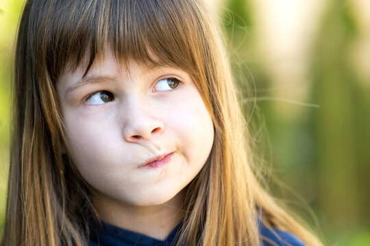 Close up portrait of pensive cute brunette child girl in park