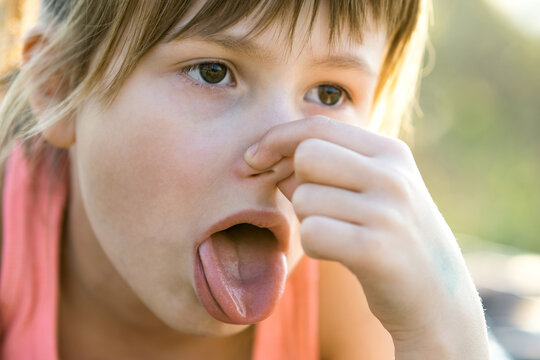 Close Up Of Portrait Beautiful Child Girl Pinching Nose And Showing Tongue.