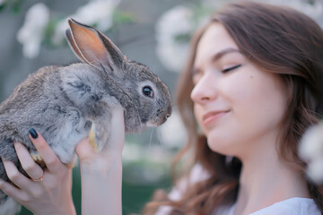 easter bunny in the hands of a beautiful girl, spring, april in a blooming garden, portrait of a woman