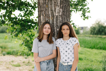 Portrait of two girlfriends in nature. Teenage girls walking in the fresh air. Summer holidays. Nature saves from quarantine. Brown hair in girls