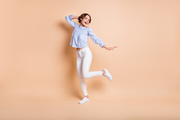 Fototapeta na wymiar Full length photo of young excited girl happy positive smile have fun dance look empty space isolated over beige color background