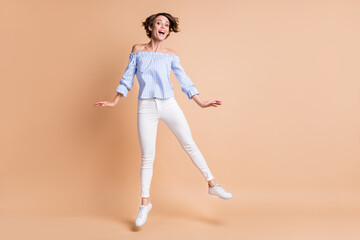 Fototapeta na wymiar Full length body size view of attractive cheerful thin girl jumping having fun isolated over beige pastel color background