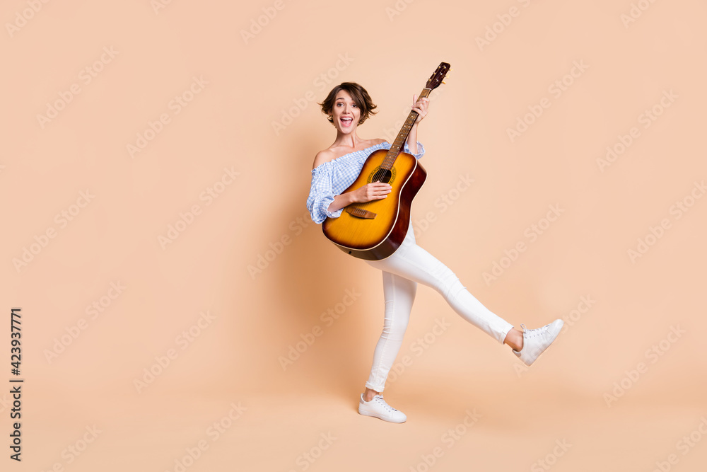 Poster Full body photo of young excited girl happy smile play guitar sing concert isolated over beige color background