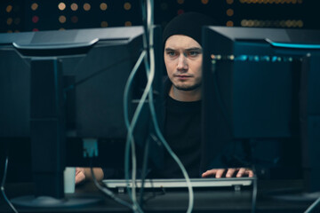 Young professional male hacker using keyboard typing bad data into computer online system and...