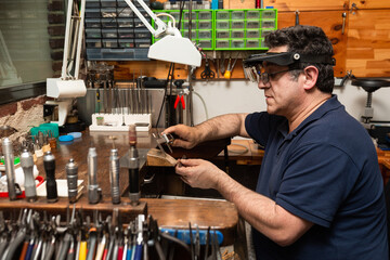 goldsmith jeweler measures with a caliper a piece of silver to make a ring