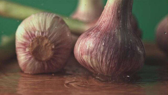 Super slow motion garlic falls on the table. On a green background. Filmed on a high-speed camera at 1000 fps.High quality FullHD footage