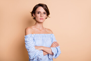 Obraz premium Photo portrait of serious woman with folded arms standing near blank space wearing glasses isolated on pastel beige colored background