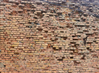 wall of old abandoned crumbling brick building without windows