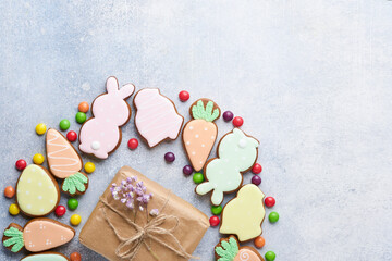 Easter eggs, cookie and colorful sweet made in shape of circle wreath on gray background. Minimal holiday concept with copy space for text. Flat lay pattern.