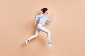 Photo portrait side view of girl running jumping up isolated on pastel beige colored background
