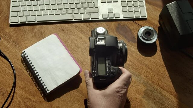 Hand takes DSLR camera and notepad from computer desk in morning light