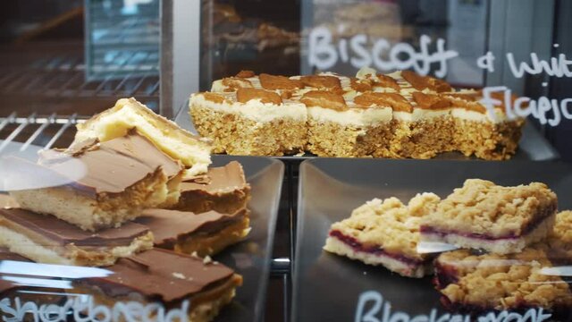 Carrot cakes, flapjacks, caramels slices and walnut cake deserts in a cafe restaurant counter bar display case.