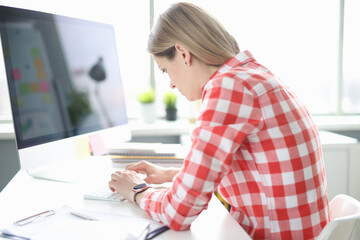 Young woman works at computer with crooked back