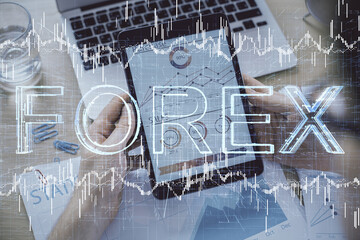 Double exposure of man's hands holding and using a digital device and forex graph drawing. Financial market concept.