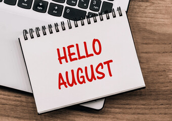 Hello August - text on a notebook against rustic wood with a laptop © Nastassia