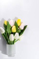 Close-up of a beautiful bouquet of white and yellow tulips in a glass vase on white background