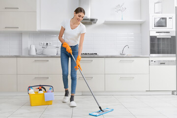 Young brunette cleaning kitchen floor.
