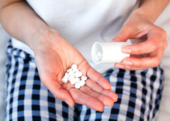 Young woman holds pills and a pill bottle into her hand. Taking medications with a doctor's prescription. Close-up.