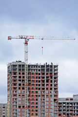 Fototapeta na wymiar Construction crane on the background of a multi-storey building under construction