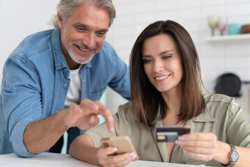 Caucasian couple involved in online shopping, entering payment information from credit bank card in mobile application