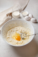 Bowl with cream cheese and egg for kneading dough. Ingredients for cooking Basque Spanish burnt Saint Sebastian cheesecake. Cream cheese, sugar, eggs, flour and cream. Recipe step by step