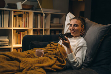 Obraz premium woman relaxing on sofa at her home and watching television