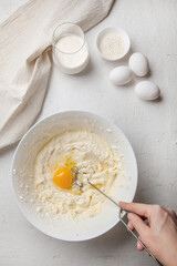 Woman kneads the dough in Bowl with cream cheese and egg. Ingredients for cooking Basque Spanish...
