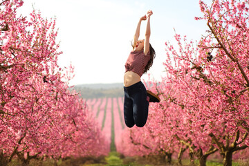 Happy woman jumping in a flowered field in spring