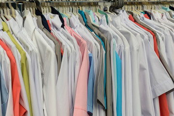 Obraz premium Hanger with white and colored clothes. The concept of overalls for doctors, hotel staff.