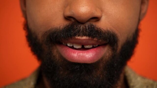 partial view of bearded of african american man pouting lips isolated on orange