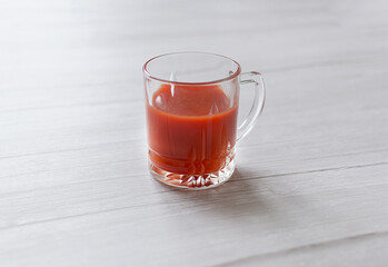 Glass of tomato juice on light background