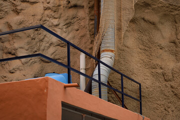 Industrial Pipework on Top of Building with Black Steel Handrail next to Rough Concrete Wall