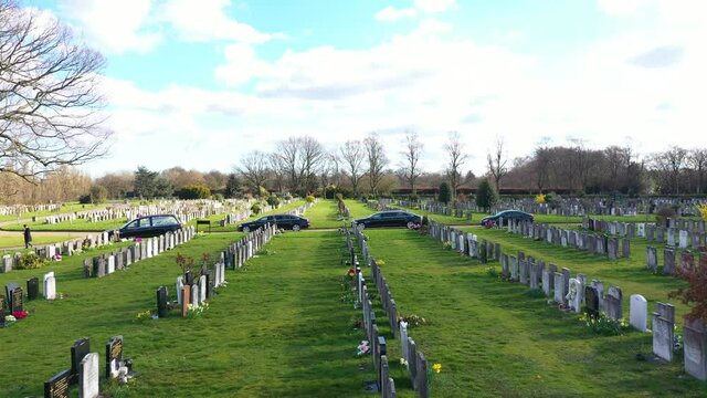 BLACK FUNERAL VEHICLES CARRYING COFFING MOVING SLOWLY AT THE CEMETERY, AERIAL