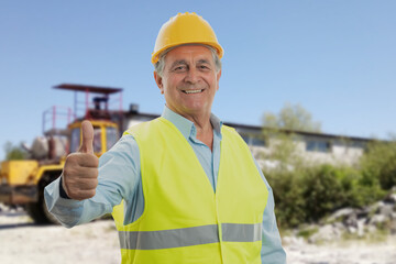 Old constructor on building site making thumb-up gesture